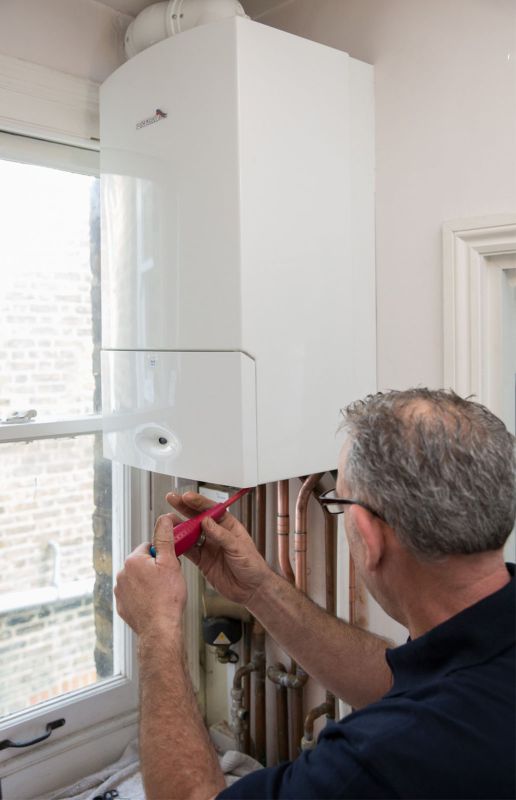 Gas Safe registered engineer repairing a boiler in a London property Gas Safe-registered engineer inspecting a boiler