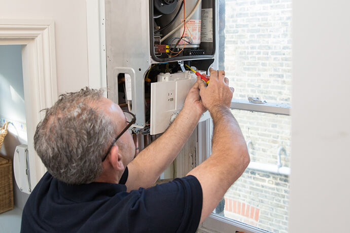 Get your central heating repair service in London today! Plumber repairing a gas boiler in London